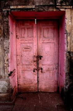 an old pink door is open on the side of a building