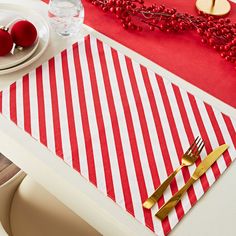 a red and white striped placemat with goldware on it next to a plate