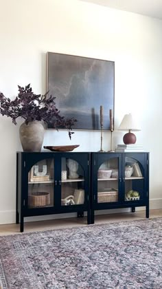 a room with a rug, vases and pictures on the wall