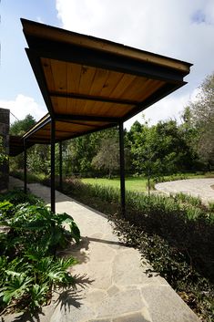 an outdoor covered walkway next to a lush green park