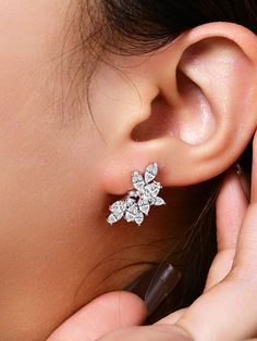 a close up of a person wearing a pair of ear clips with flowers on them