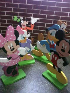 mickey and minnie mouse figurines lined up in front of a brick wall,