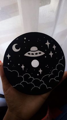 a person holding up a black and white plate with stars and planets in the sky