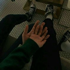 two people are sitting on the floor with their feet up and one person is holding his hand out