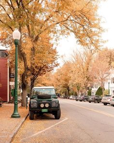 the jeep is parked on the side of the road near the street lamp and trees