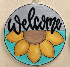 a sunflower painted on the side of a wall next to a sign that says welcome