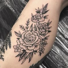 a black and white flower tattoo on the left arm, with leaves around it's edges