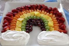 a rainbow cake with fruit and whipped cream