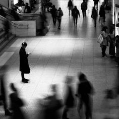 many people are walking around in the mall and one person is looking at his cell phone