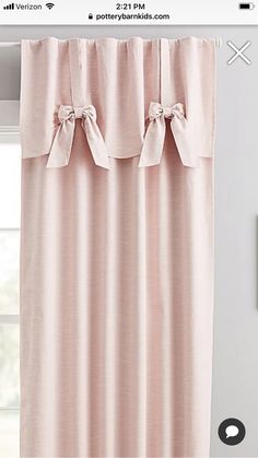 a pink curtain hanging on the side of a window with two bowknots