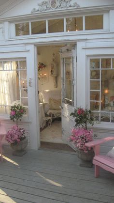 two pink chairs sitting on top of a wooden deck next to flowers and potted plants