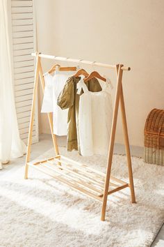 a clothes rack with two shirts hanging from it's sides, in front of a window