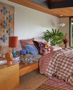 a bed room with a neatly made bed and a plant on the side of it