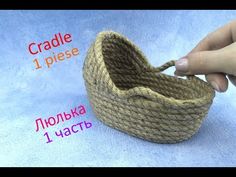 a hand is holding a rope basket with two sides and the other side has an open lid