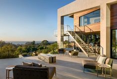 an outdoor living area with couches, chairs and stairs leading up to the balcony