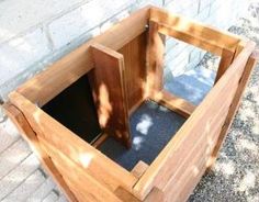 a wooden planter sitting on top of a sidewalk next to a brick wall and tree