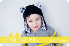 a young boy wearing a black and yellow hat with ears on it's head