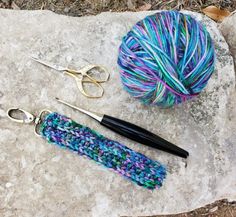 some yarn and scissors are laying on a rock