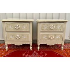 two white nightstands sitting next to each other on top of a red area rug