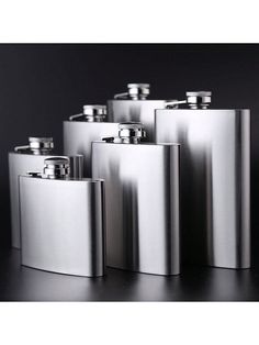 four stainless steel flasks sitting next to each other on a black table top