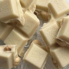 several pieces of white chocolate sitting on top of a plastic container with nuts in it