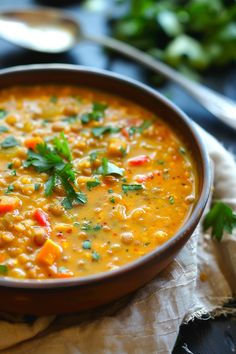 A bowl of lentil soup garnished with chopped parsley and accompanied by a spoon and herbs in the background. Glazed Meatballs, Spicy Appetizers