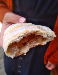 a person holding a half eaten pastry in their left hand and wearing an orange shirt