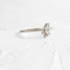 6x3mm marquise cut white diamond focal (SI1 clarity, G+ color) Three SI clarity white accent diamonds (1-2mm) Solid 14k gold setting with a delicate 1.2mm tapered round band (available in yellow, rose, and white) Total carat weight: .28ct. We handcraft each piece with responsibly sourced 14k gold and ethically sourced stones. Timeless Sterling Silver Diamond Ring With Rose Cut, Timeless Marquise Sterling Silver Ring, Delicate Diamond Marquise Cut Ring, Diamond White Cluster Ring With Single Cut Moissanite, Diamond White Single Cut Lab Grown Diamond Ring, Minimalist White Diamond Ring With Single Cut Diamonds, White Minimalist Diamond Ring With Single Cut Diamonds, Delicate White Gold Diamond Ring With Single Cut Diamonds, Marquise Cut Lab-grown Diamond Ring With Single Cut Diamonds