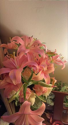 a bouquet of pink lilies sitting on top of a table next to other flowers