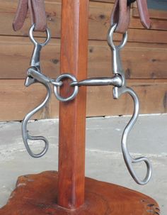 a horse bridle is attached to a wooden pole with two metal chains hanging from it