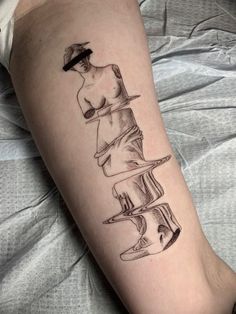 a woman's leg with a tattoo on it that has books stacked in the shape of a stack