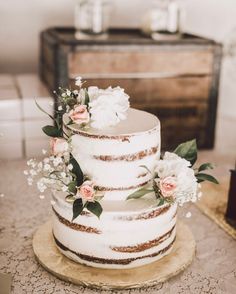 a three tiered cake with flowers and greenery sits on top of a table