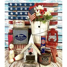 patriotic items are displayed on a table with an american flag and flowers in a bucket