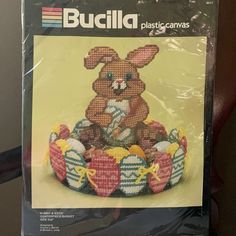 a cross stitch pattern for an easter bunny with eggs in it's basket and the words, bucilla plastic canvass