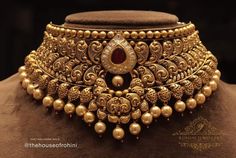 a gold necklace with pearls and an ornate design on the collar, which is adorned with a