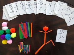 several pieces of paper are arranged on a table with markers and pom poms