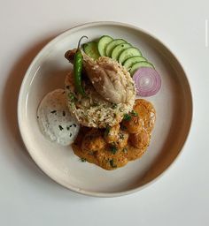 a white plate topped with food and cucumbers on top of eachother