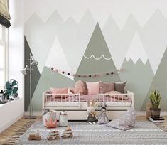 a room with mountains painted on the wall and pink pillows in the bedding area