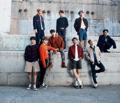 a group of young men sitting next to each other on top of a cement wall