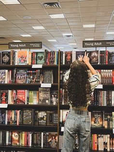 a woman standing in front of a bookshelf with her hands up to the ceiling