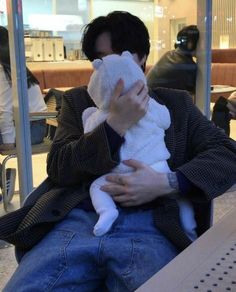 a man holding a stuffed animal in his hands while sitting down at an airport terminal