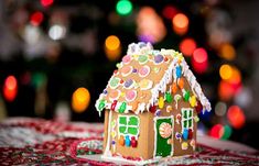 a gingerbread house on a table with christmas lights in the background