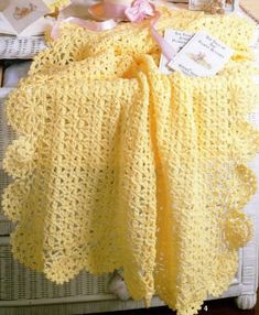 a crocheted yellow blanket sitting on top of a white basket next to other items