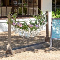 there are many vases with flowers in them hanging from the poles and on the ground