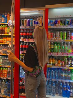 a woman standing in front of a refrigerator filled with drinks