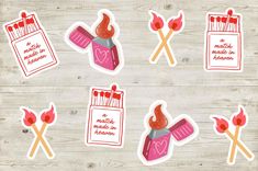 some stickers with different things in them on a wooden surface, including scissors and matchesticks