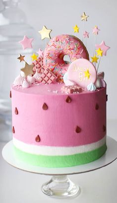 a pink and green birthday cake with donuts, sprinkles and stars