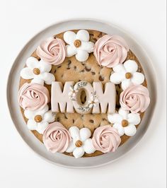 a mother's day cake decorated with pink and white flowers on a gray plate