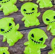 cookies decorated with neon green frosting and spooky eyes are arranged on a wooden table