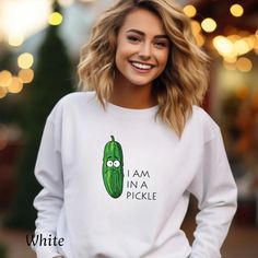 a smiling woman wearing a white sweatshirt with a pickle on it's chest